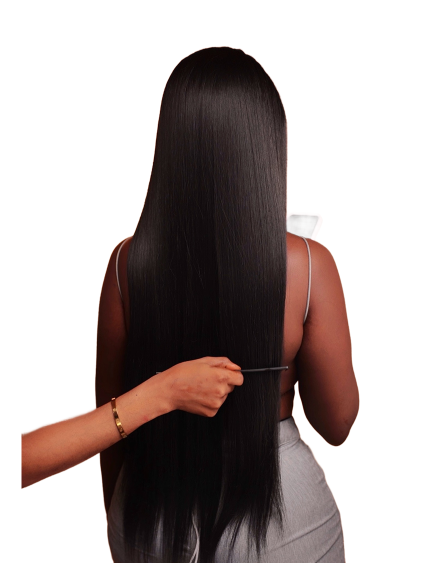 A person with long, straight, shiny black hair—resembling affordable wigs—faces away from the camera. Another hand uses a comb to gently part or style the hair near the lower back. The background is plain white.